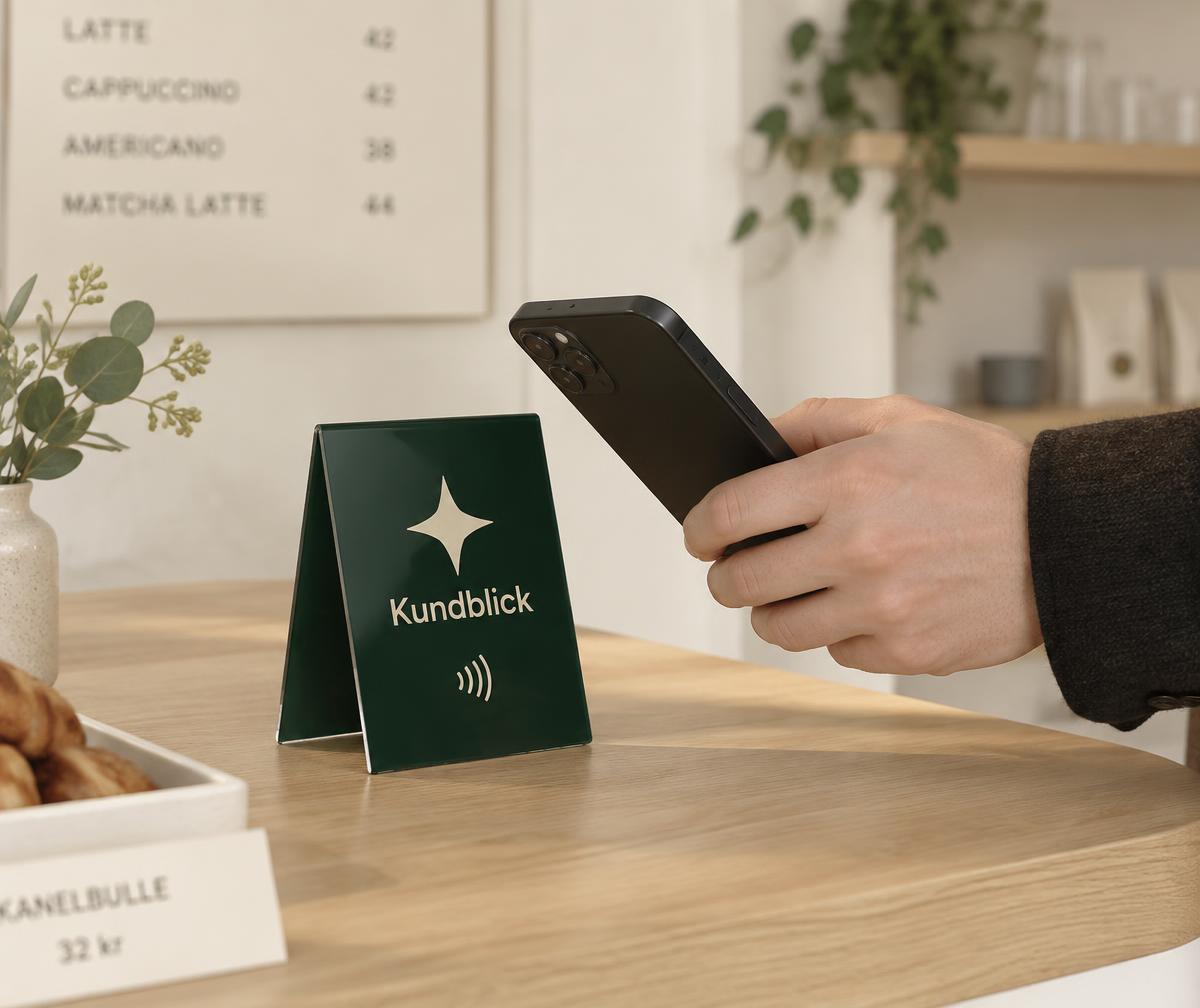 Kund blippar mobilen mot en Kundblick-skylt på en caféskänk